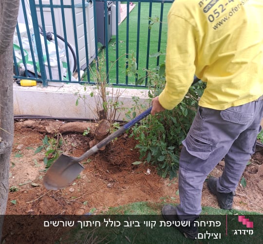 אדם חופר באדמה עם את חפירה ליד גדר מתכת